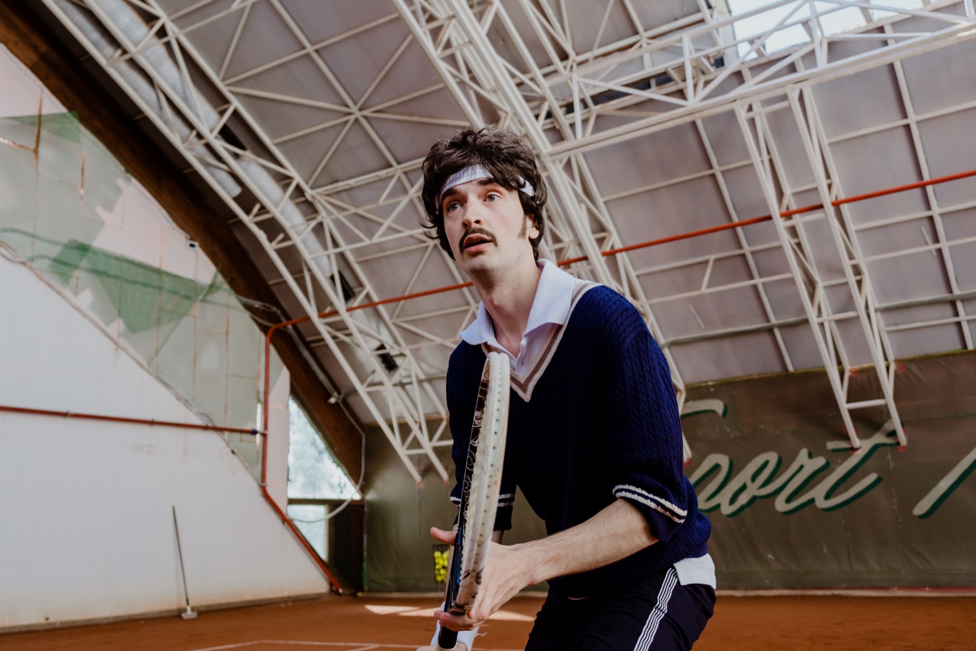 A tennis player holding a racket on an indoor court.